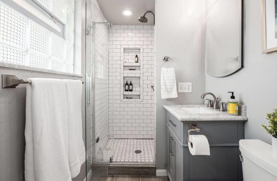 Cornerstone Ranch Primary Bathroom after renovations. Grey vanity with marble top and white subway tile shower with glass door.